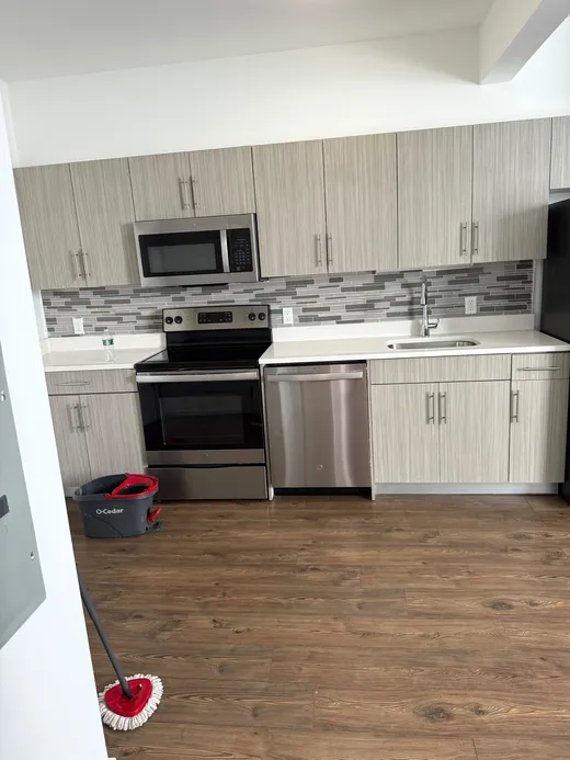 An apartment kitchen mid move-out clean, mop and bucket in place
