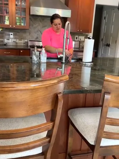A Milu team member in a pink tee wiping a kitchen island